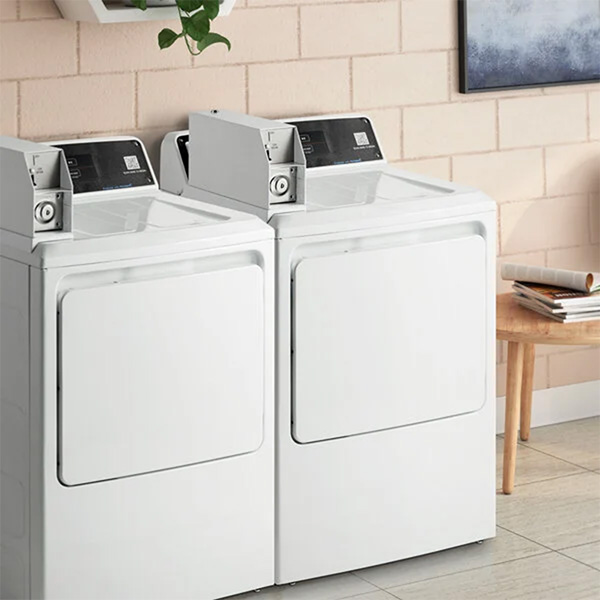 GE Appliances Commercial Laundry set installed in laundry room with blush subway tile wall and styled decor